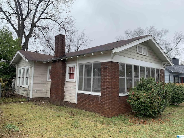 view of side of home with a sunroom and a yard