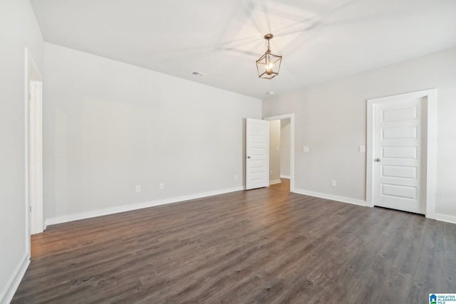 unfurnished room featuring an inviting chandelier and dark wood-type flooring