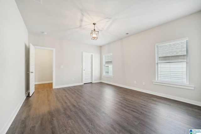 unfurnished room featuring dark hardwood / wood-style flooring and a notable chandelier