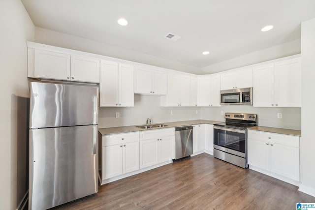 kitchen with dark hardwood / wood-style floors, sink, white cabinetry, and stainless steel appliances