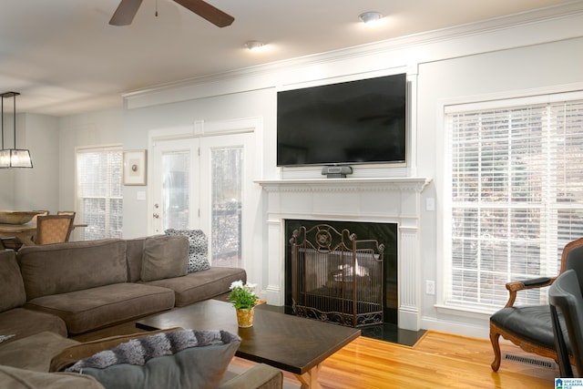 living room with hardwood / wood-style floors, ceiling fan, ornamental molding, and a premium fireplace