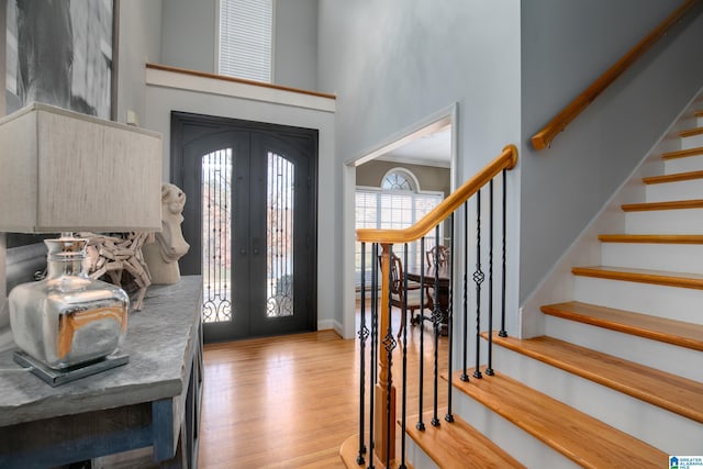 foyer entrance featuring french doors, a towering ceiling, and light hardwood / wood-style floors