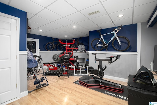 exercise room featuring wood-type flooring and a drop ceiling