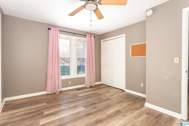 unfurnished bedroom featuring wood-type flooring, a closet, and ceiling fan