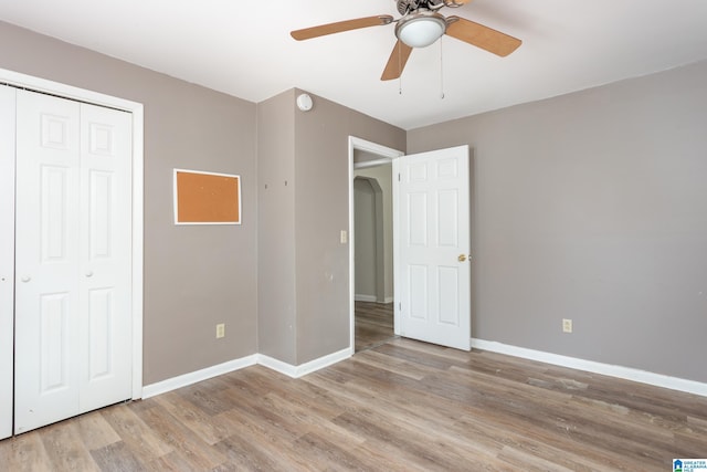 unfurnished bedroom featuring a closet, light hardwood / wood-style flooring, and ceiling fan