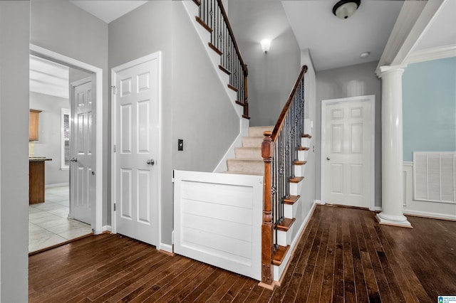 stairs featuring decorative columns and wood-type flooring