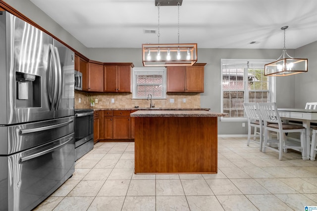 kitchen featuring pendant lighting, a center island, appliances with stainless steel finishes, tasteful backsplash, and a notable chandelier