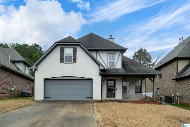 tudor home with a porch, a garage, and central air condition unit