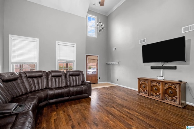 living room featuring hardwood / wood-style floors, a towering ceiling, ceiling fan with notable chandelier, and ornamental molding