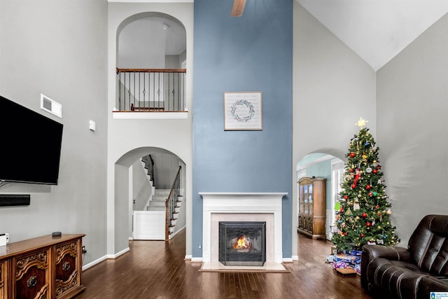 living room with high vaulted ceiling and dark wood-type flooring