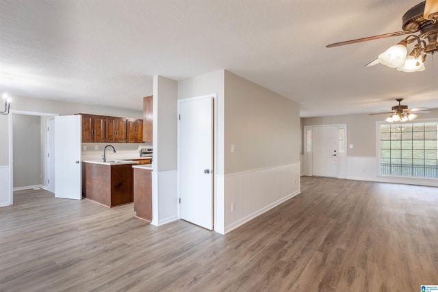 unfurnished living room with wood-type flooring, a textured ceiling, ceiling fan, and sink