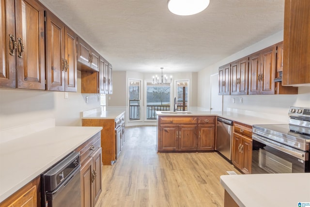 kitchen with light hardwood / wood-style flooring, kitchen peninsula, a chandelier, pendant lighting, and appliances with stainless steel finishes