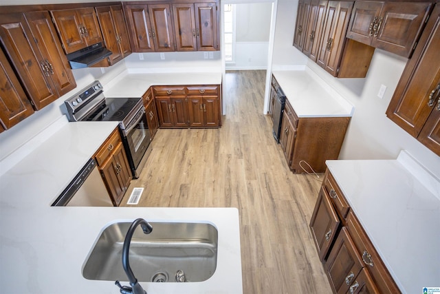 kitchen with appliances with stainless steel finishes, light wood-type flooring, and range hood