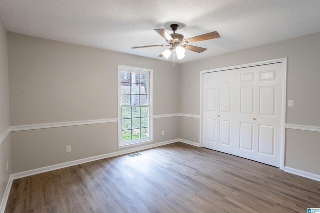 unfurnished bedroom with hardwood / wood-style floors, a textured ceiling, a closet, and ceiling fan