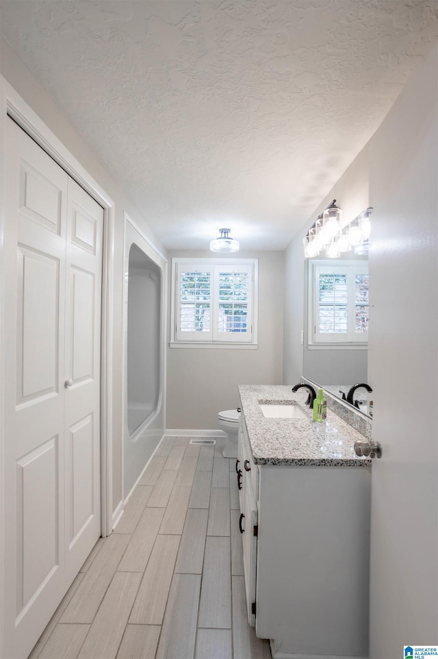 bathroom with vanity, toilet, and a textured ceiling