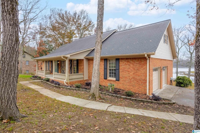 view of side of home featuring a water view, covered porch, and a garage