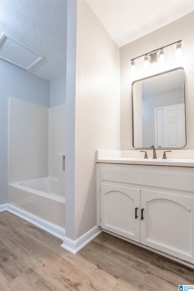 bathroom featuring wood-type flooring, vanity, a textured ceiling, and bathing tub / shower combination