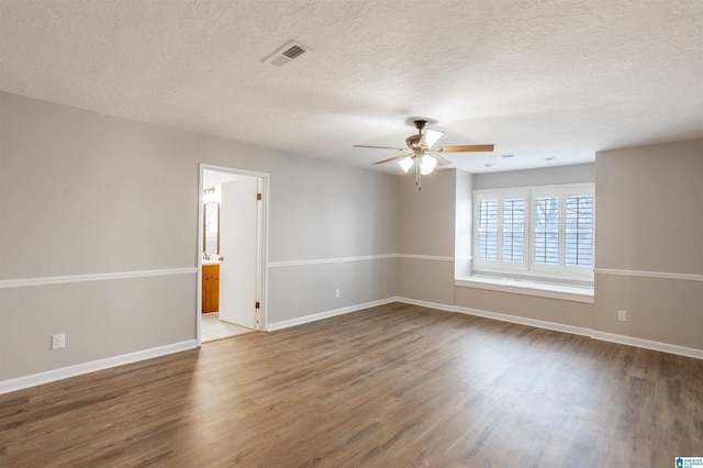 empty room with ceiling fan, wood-type flooring, and a textured ceiling