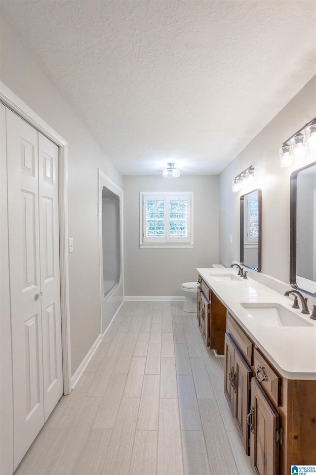 bathroom featuring a textured ceiling, vanity, and toilet