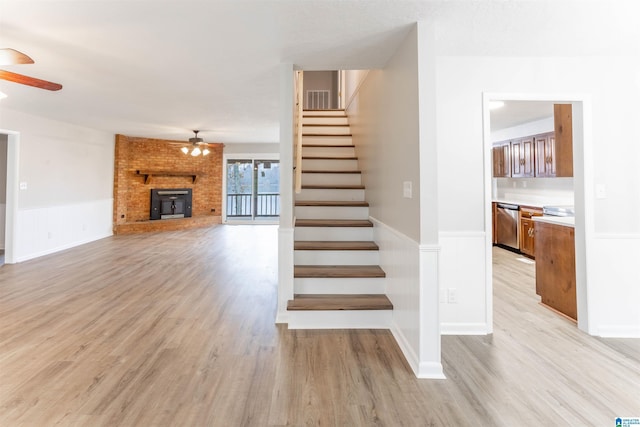 stairway with a wood stove, ceiling fan, and hardwood / wood-style flooring