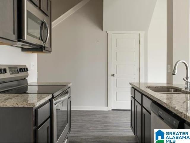 kitchen featuring light stone countertops, sink, dark hardwood / wood-style floors, and appliances with stainless steel finishes