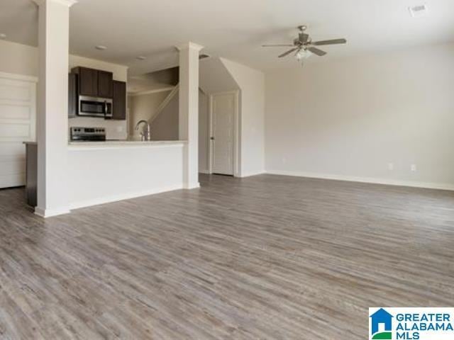 unfurnished living room with ceiling fan and dark wood-type flooring