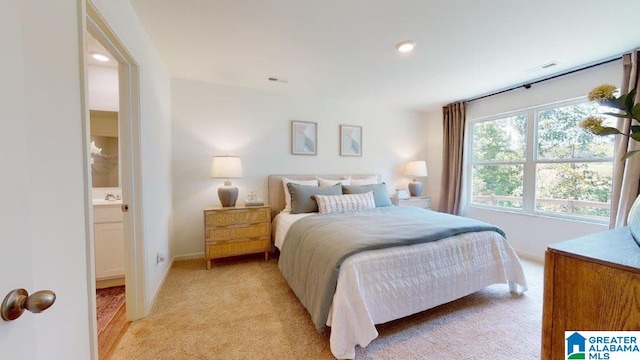 bedroom featuring ensuite bathroom and light colored carpet