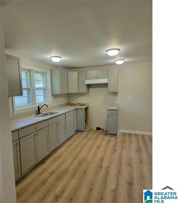 kitchen with light hardwood / wood-style flooring, gray cabinetry, and sink