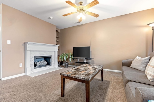 carpeted living room with ceiling fan, a fireplace, and built in features