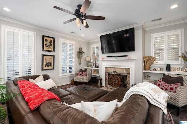 living room featuring hardwood / wood-style floors, ceiling fan, a premium fireplace, and crown molding