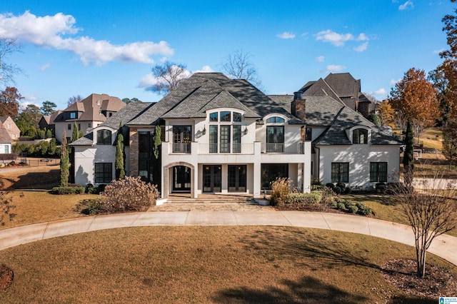 french country home featuring a balcony and a front yard