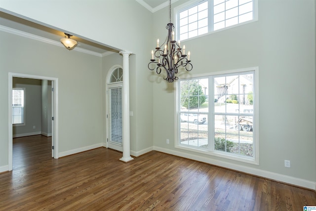 unfurnished room with dark wood-type flooring, a wealth of natural light, and decorative columns