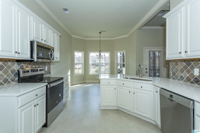 kitchen featuring white cabinetry, sink, stainless steel appliances, a notable chandelier, and kitchen peninsula