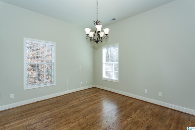 empty room with a chandelier and dark hardwood / wood-style floors