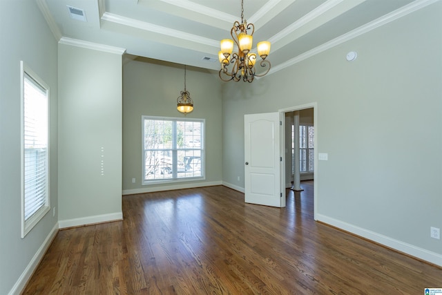 empty room with a tray ceiling, a chandelier, dark wood-type flooring, and ornamental molding