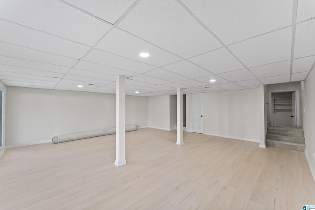 basement with a paneled ceiling and light hardwood / wood-style floors