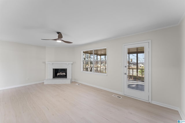 unfurnished living room with a fireplace, light hardwood / wood-style floors, ceiling fan, and crown molding