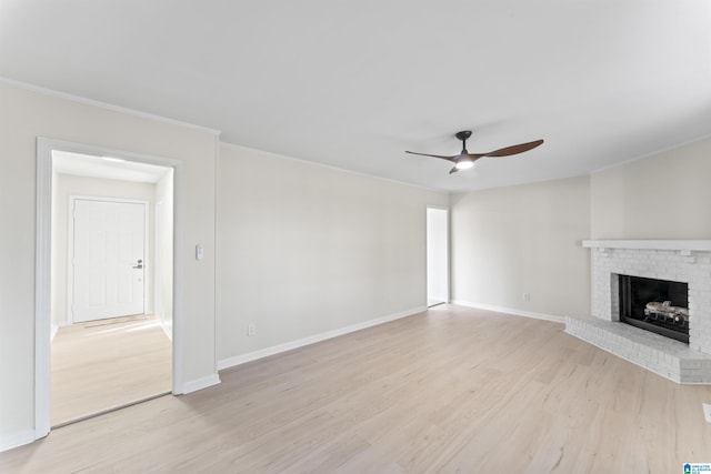 unfurnished living room featuring ceiling fan, light hardwood / wood-style flooring, ornamental molding, and a brick fireplace