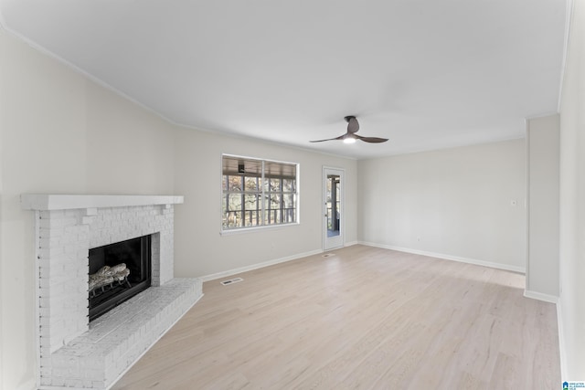 unfurnished living room featuring ceiling fan, a fireplace, crown molding, and light hardwood / wood-style flooring