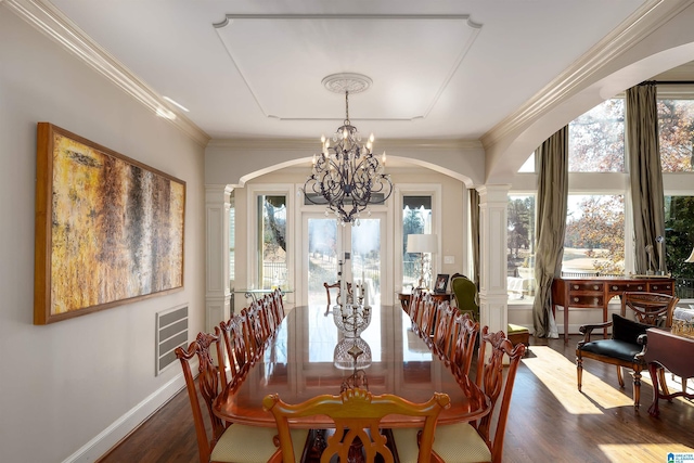 dining space with ornate columns, dark hardwood / wood-style flooring, ornamental molding, an inviting chandelier, and french doors