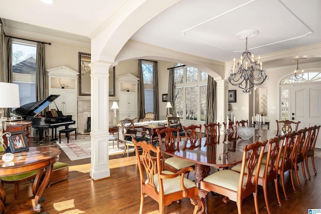 dining room featuring a notable chandelier, a healthy amount of sunlight, and ornate columns