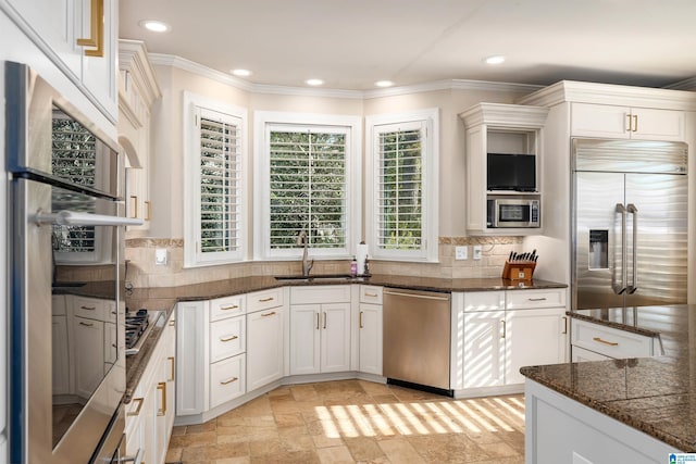 kitchen featuring built in appliances, sink, decorative backsplash, and white cabinets