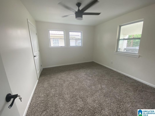 spare room featuring ceiling fan and dark carpet