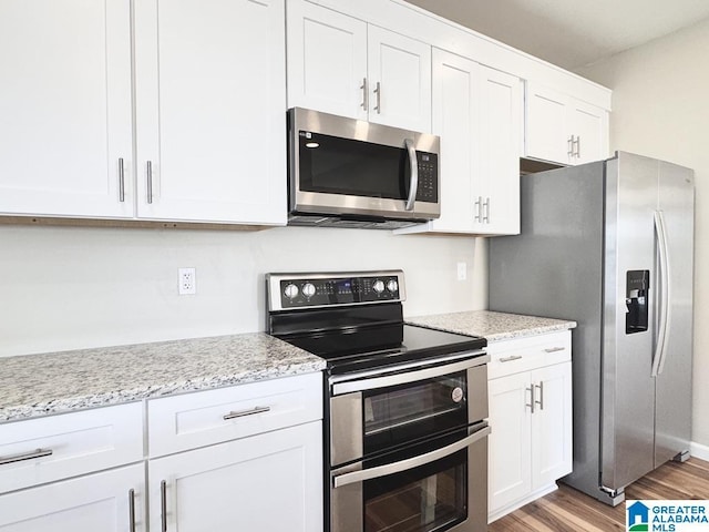 kitchen with white cabinets, light stone countertops, light wood-type flooring, and appliances with stainless steel finishes