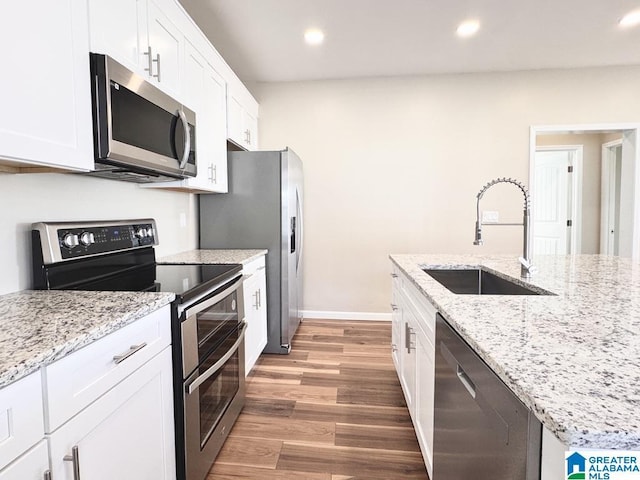 kitchen with light stone countertops, sink, dark wood-type flooring, white cabinets, and appliances with stainless steel finishes