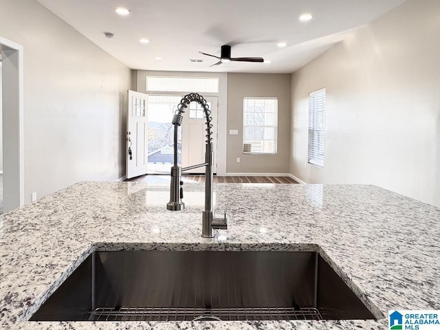 interior details featuring light stone counters, sink, and ceiling fan