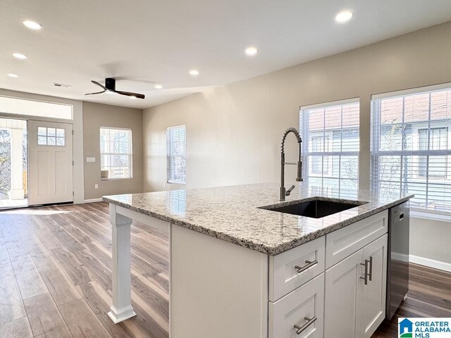 kitchen featuring light stone countertops, plenty of natural light, white cabinets, and sink