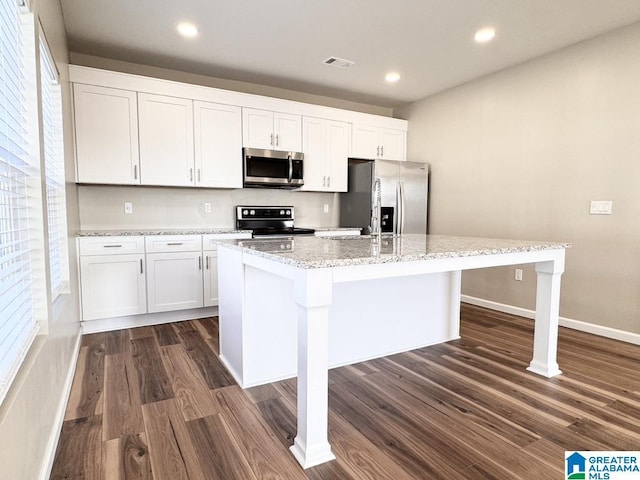 kitchen featuring dark wood-type flooring, white cabinetry, a center island with sink, and stainless steel appliances