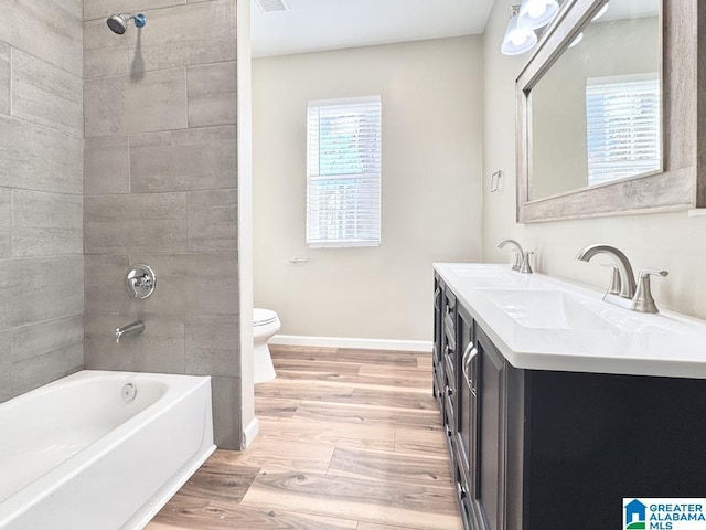 full bathroom with vanity, tiled shower / bath combo, hardwood / wood-style flooring, and toilet