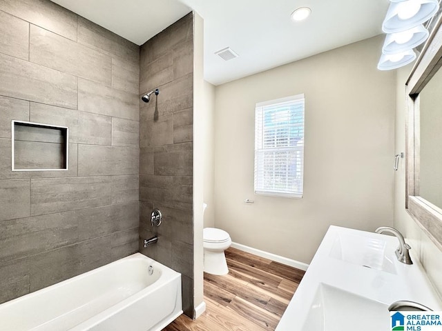 full bathroom with vanity, hardwood / wood-style flooring, toilet, and tiled shower / bath